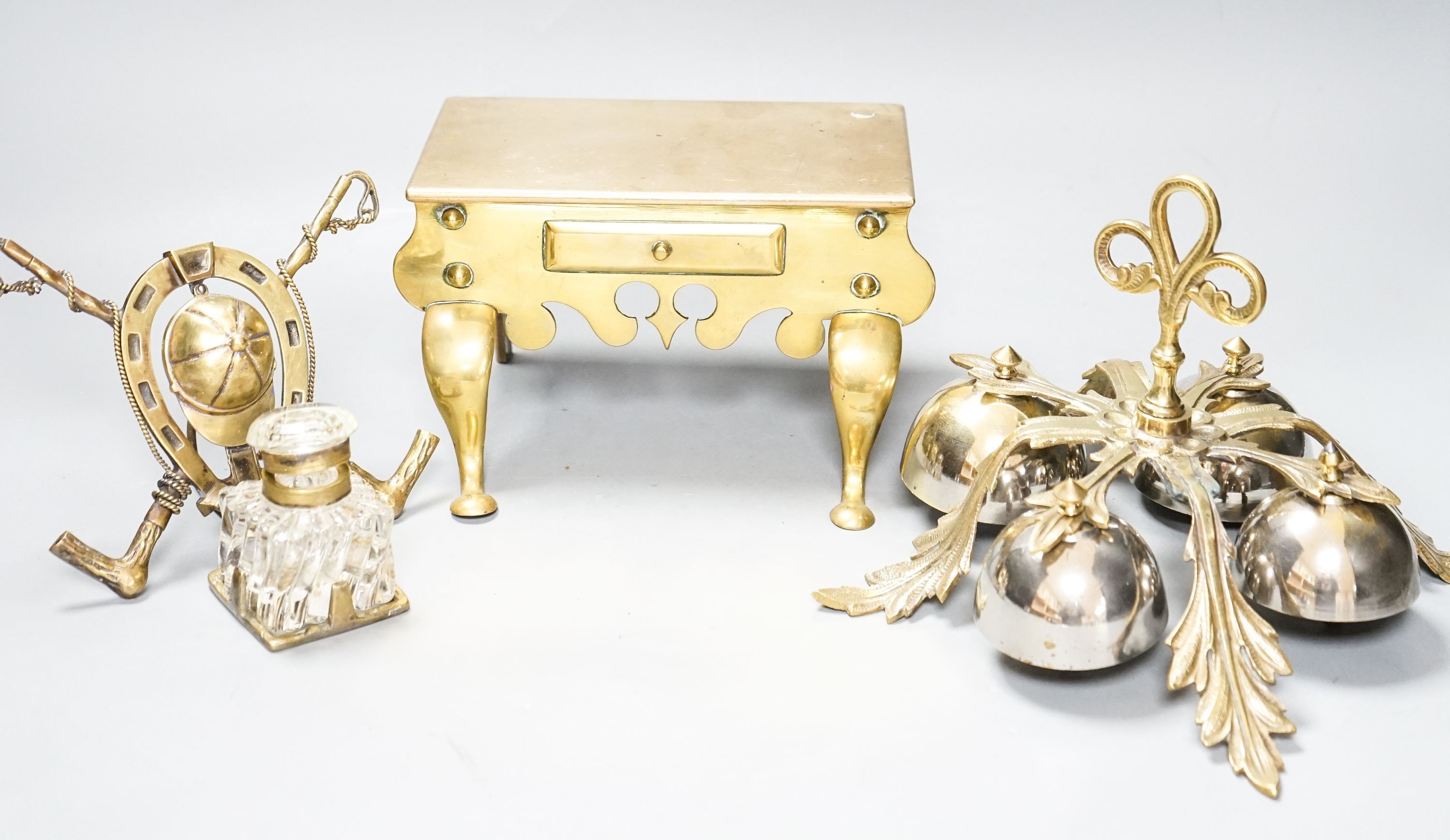 A brass Jockey-related inkwell, a miniature brass footman and brass hand bells